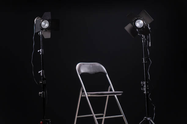 istock Empty black chair in front two two led spot lights, black background 1192101332