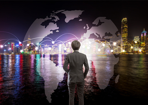 Looking for the world future and connection opportunity concept, Business man standing and looking in front of blur cityscape by the sea background with white dots connection communication lines and world map