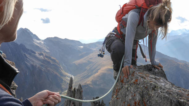 istock Female mountaineer scrambles up mountain ridge 1192101680