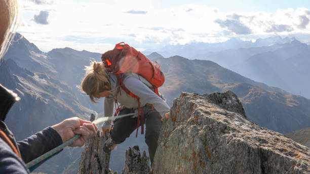 istock Female mountaineer scrambles up mountain ridge 1192101865
