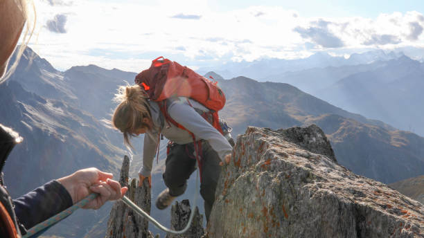 istock Female mountaineer scrambles up mountain ridge 1192101896
