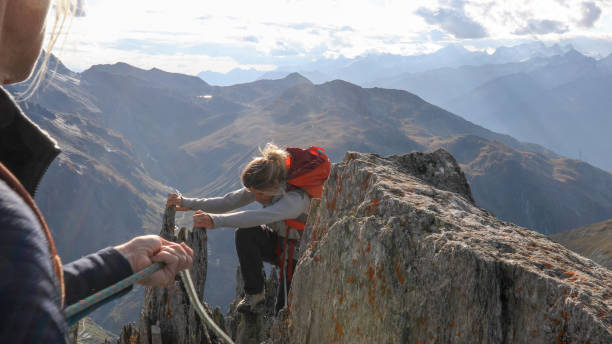 istock Female mountaineer scrambles up mountain ridge 1192101942