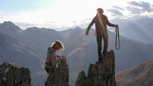 o montanhista fêmea scrambles acima do cume da montanha - climbing rock climbing women determination - fotografias e filmes do acervo