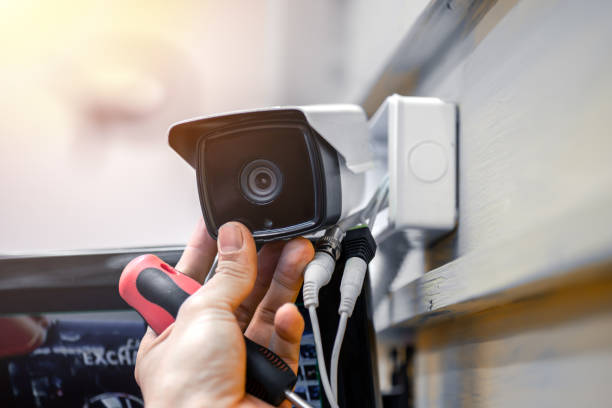 Close-up of surveillance camera installation, male hand holds cctv camera Close-up of surveillance camera installation, male hand holds cctv camera security system stock pictures, royalty-free photos & images