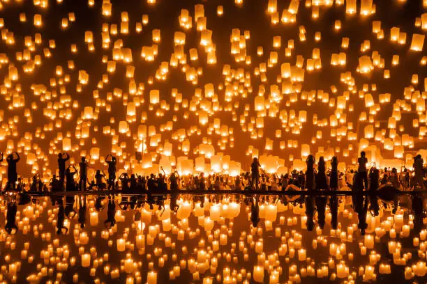 Photo of Thai people release sky floating lanterns or lamp to worship Buddha's relics with reflection. Traditional festival in Chiang mai, Thailand. Loy krathong and Yi Peng Lanna ceremony. Celebration.