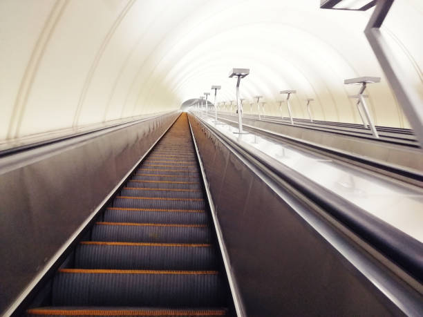 istock Descent into the tunnel stereo escalator stairs light from below. Modern tunnel escalator electronic system moving vintage style, Mechanical escalators for people up and down 1192104659