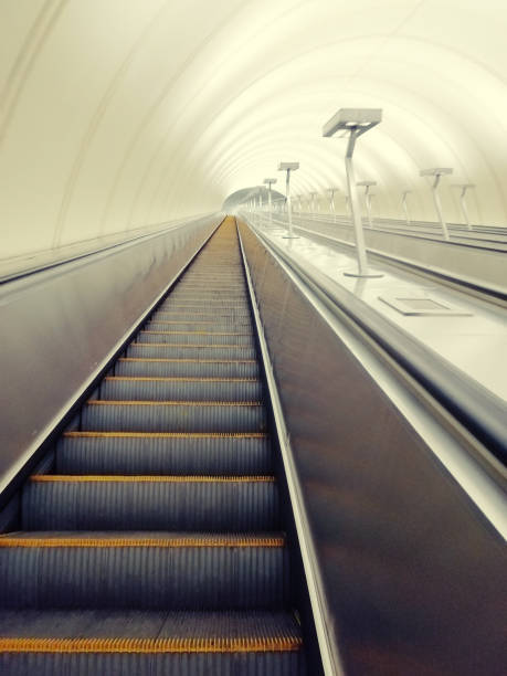 istock Descent into the tunnel stereo escalator stairs light from below. Modern tunnel escalator electronic system moving vintage style, Mechanical escalators for people up and down 1192104665