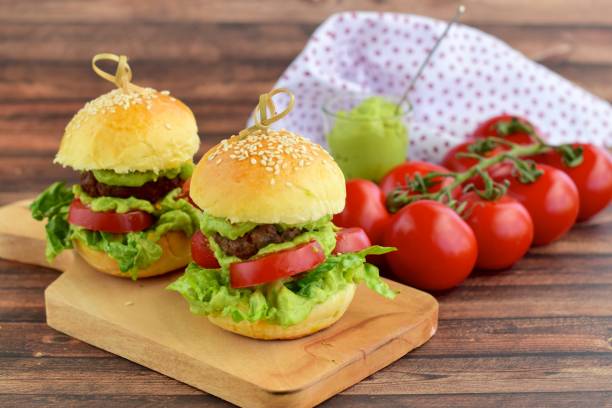 Sesame seed burger buns with beef patties, guacamole, tomato and lettuce