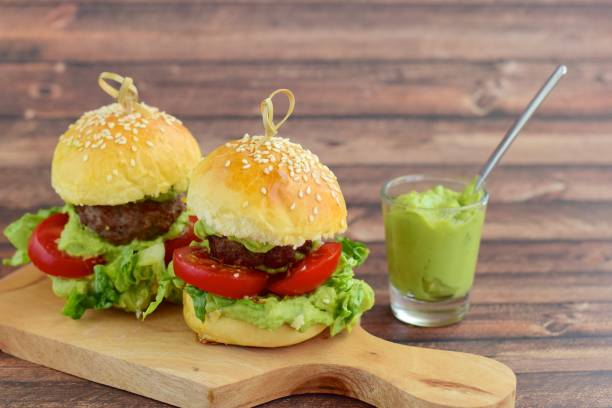 Sesame seed burger buns with beef patties, guacamole, tomato and lettuce