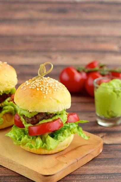 Sesame seed burger buns with beef patties, guacamole, tomato and lettuce