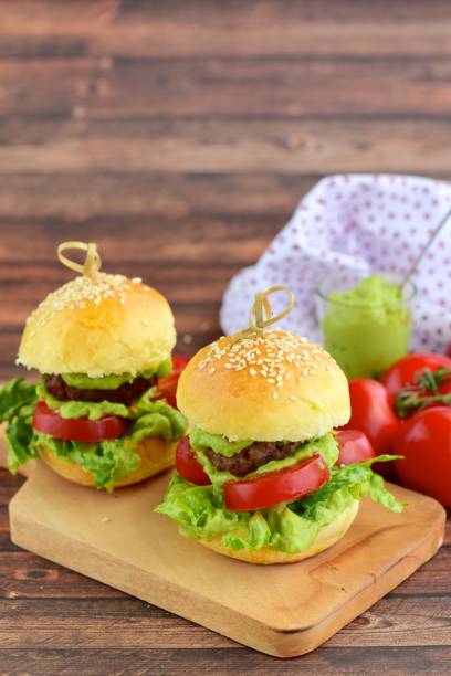 Sesame seed burger buns with beef patties, guacamole, tomato and lettuce