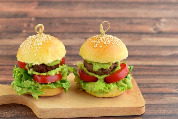 Sesame seed burger buns with beef patties, guacamole, tomato and lettuce