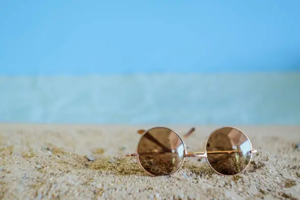 Sunglasses eyeware drop on tropical sand beach.