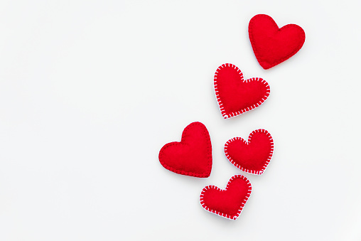 Red felt hearts on white background. Valentines day or Woman's day holidays concept. Top view.