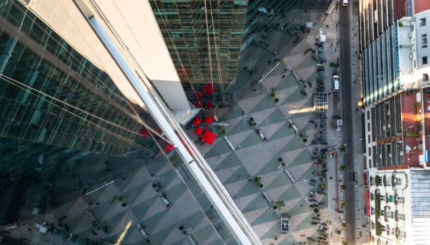 istock Skyscraper reflection in a glass building with red umbrellas on the ground floor 1192106478