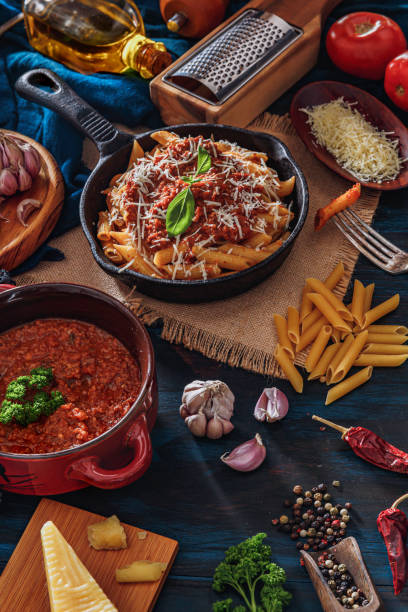 istock Penne with Bolognese sauce in serving size casserole with ingredients in rustic pots 1192109201