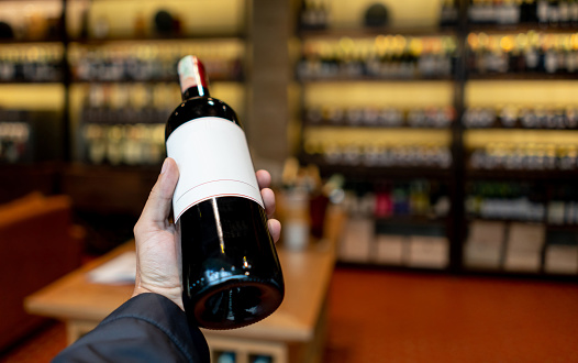Close-up on a sommelier holding a bottle of wine at a cellar