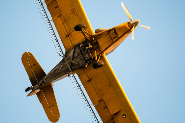 istock Yellow Crop Dusting Plane Flying in a Blue Sky 1192109405