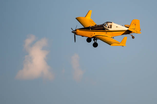 istock Yellow Crop Dusting Plane Flying in a Blue Sky 1192109417