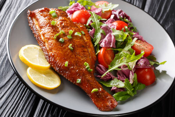 メインディッシュフライドロックフィッシュは、新鮮な野菜サラダを皿にクローズアップして提供しました。水平 - prepared fish fish grilled close up ストックフォトと画像