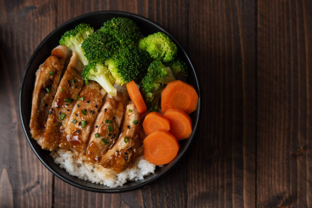 japanese food style : top view of homemade chicken teriyaki grilled with rice , carrot , broccoli put on the black bowl and place on wooden table - teriyaki broccoli carrot chicken imagens e fotografias de stock