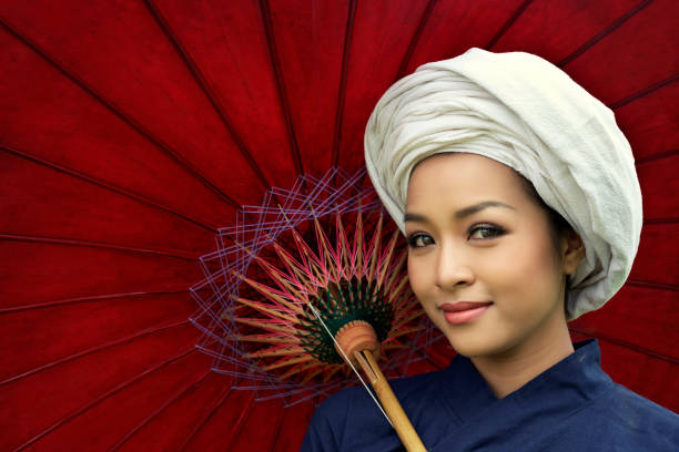 Closeup beautiful young woman wearing traditional dress with turban smiling on red umbrella background.