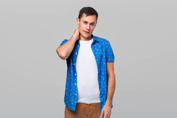 istock Unsure man stroking neck expressing doubtful emotion over grey background 1192114814
