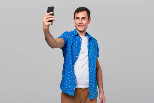 istock Handsome man making selfie with a mobile phone isolated over grey background. 1192114833
