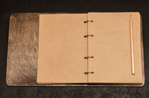 istock Eco friendly open notebook in wooden cover with blank sheets with space for your text and pencil on black background 1192115491