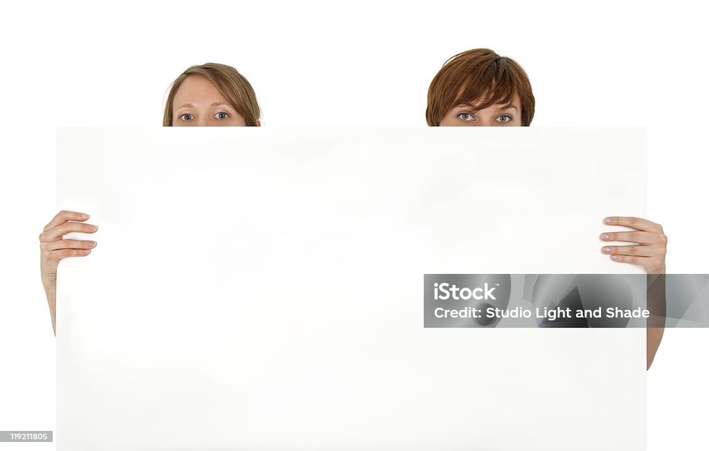 Two young women behind a blank banner ad Two young women behind a blank banner ad, on white background. Adult Stock Photo