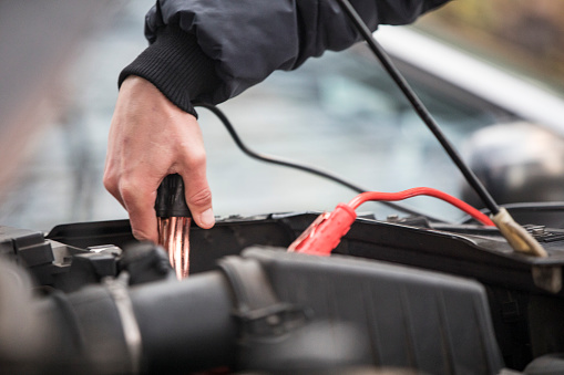 Adult Man Using Jumper Cables To Jump Start Engine of a Car.