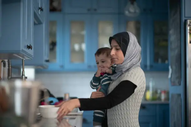 Photo of Muslim Mother and Working in the Kitchen With Infant stock photo