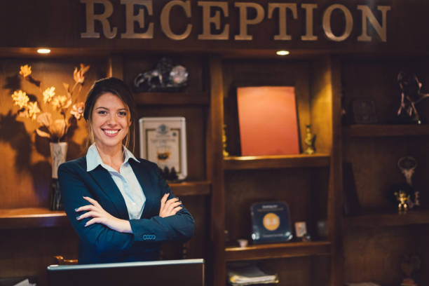 receptionist sorridente alla reception dell'hotel - women customer service representative service standing foto e immagini stock