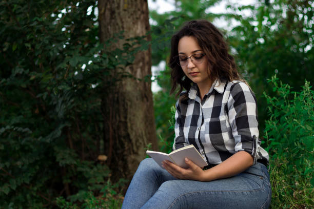 istock girl in the park reads a book 1192128624