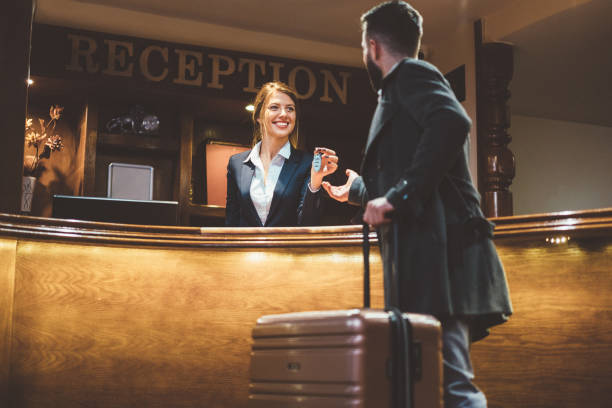 Receptionist giving keys to hotel guest Man just arriving in hotel and receiving keys from his room after check-in hotel reception stock pictures, royalty-free photos & images