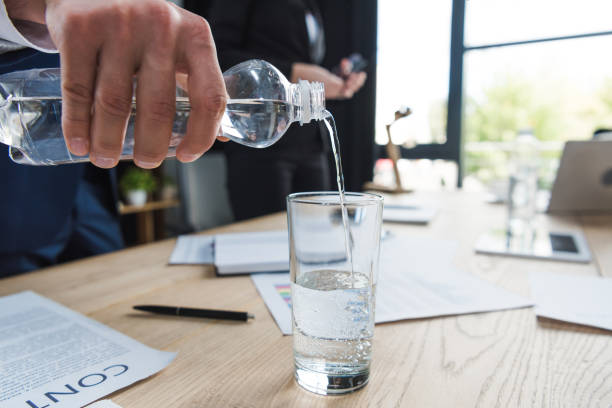 vista recortada del hombre de negocios vertiendo agua en vidrio - office water business meeting fotografías e imágenes de stock