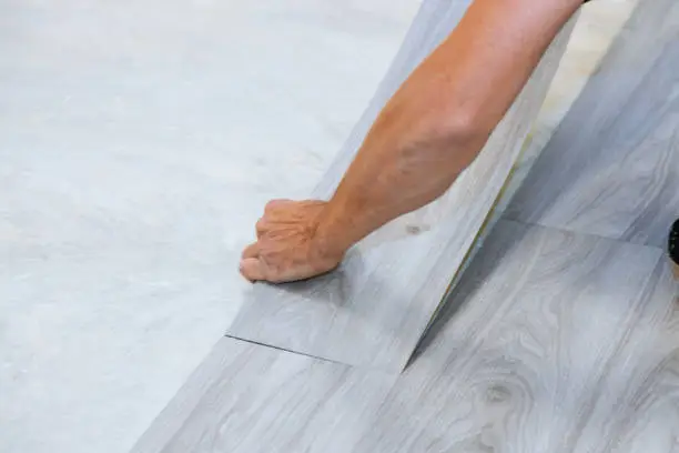 Photo of Worker installing new vinyl tile floor laminate wood texture floor with new home improvement