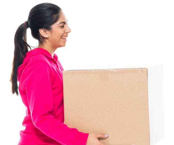 Side view / profile view / one person / waist up / portrait of 20-29 years old adult beautiful black hair / long hair generation z female / young women wearing hooded jacket / shirt / sweatshirt / pants who is smiling / happy / cheerful / laughing who is moving office / picking up and holding cardboard box / cardboard / box - container / package / container / torn vista lateral / vista de perfil / una persona / cintura para arriba / retrato de 20-29 años adulto hermoso pelo negro / largo pelo generación z mujer / mujeres jóvenes que llevan chaqueta con capucha / camisa / sudadera / pantalones que sonríe / feliz