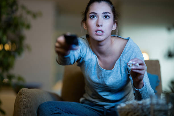 istock Shocked woman changing channels while watching TV at night. 1192141414