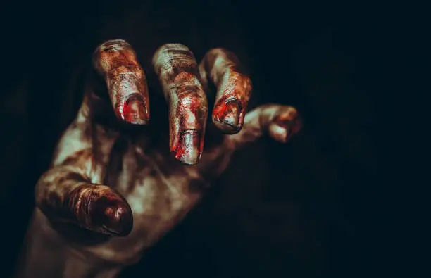 Photo of Bloody dirty zombie hand on black background. Halloween spooky poster