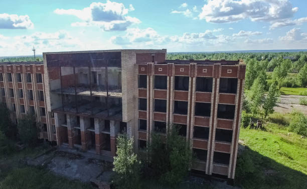 istock An old abandoned high rise building, overgrown with trees and grass. 1192144520