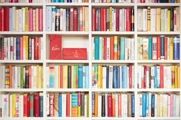 istock Library, white shelves, multi colored books,  one part filled with red gift wrap, with love 1192144737