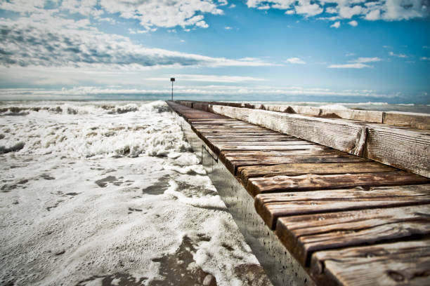 Mighty waves of the sea Waves goes through the docks cielo minaccioso stock pictures, royalty-free photos & images