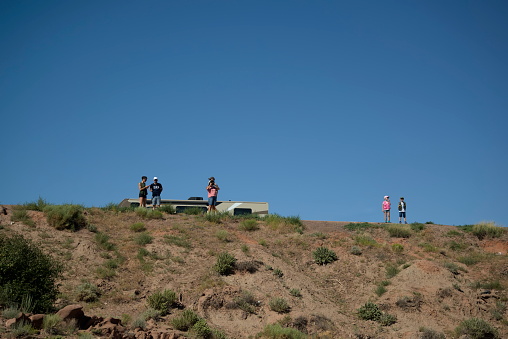 South Rim Canyon de Chelly National Park, July 7, 2019: Family of tourist on rim overlooking canyon.  A scandinavian family, four adults and two children, on a vacation at Canyon de Chelly south rim.  The children are twins, there are two adult men and two adult women, one of which is using her cell phone, the other taking pictures of the view.  Their RV motorhome is in the background.