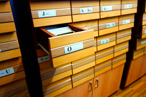 istock Hand that holds documents from an open drawer on a wooden archival old library catalog 1192146650