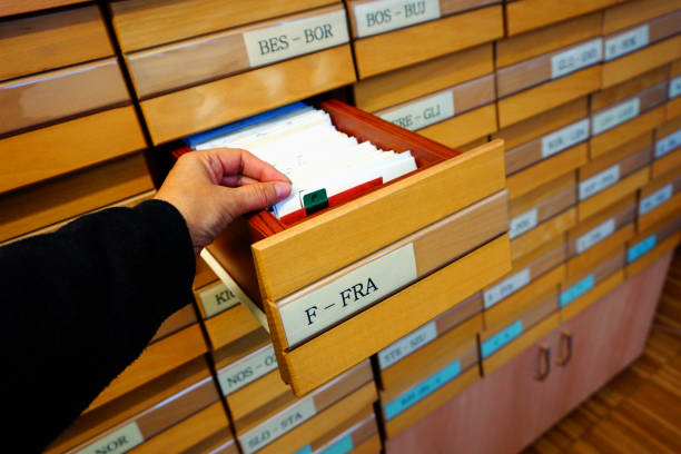 istock Hand that holds documents from an open drawer on a wooden archival old library catalog 1192146665