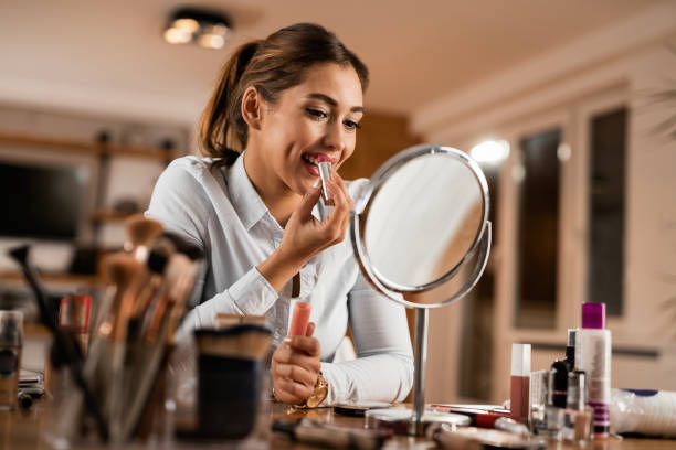 istock Beautiful woman using lipstick while looking herself in a mirror. 1192148477
