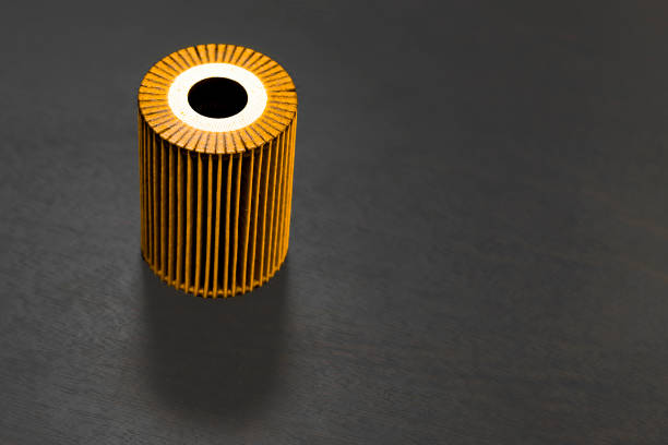 Yellow paper oil filter element on dark background. Auto part. Copy space. Front view from above.