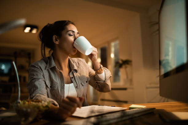 istock Female freelancer drinking coffee while working late at home. 1192151308