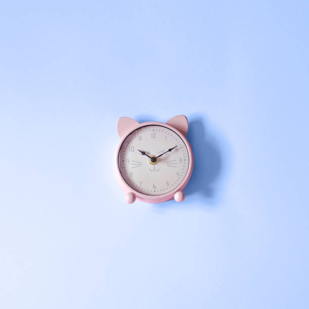 istock A clock in the shape of a cat on a classic blue background. 1192151728